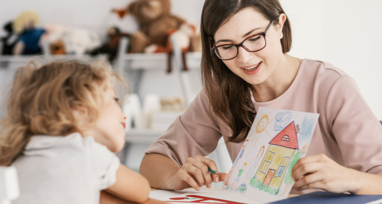 Mujer mostrando un dibujo de una casa a una niña