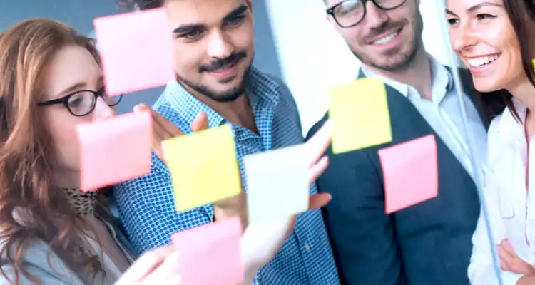 Personas pegando papeles de colores en un vidrio