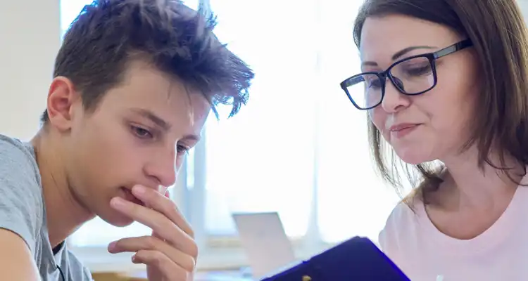 Una mujer mostrando un libro a un adolescente